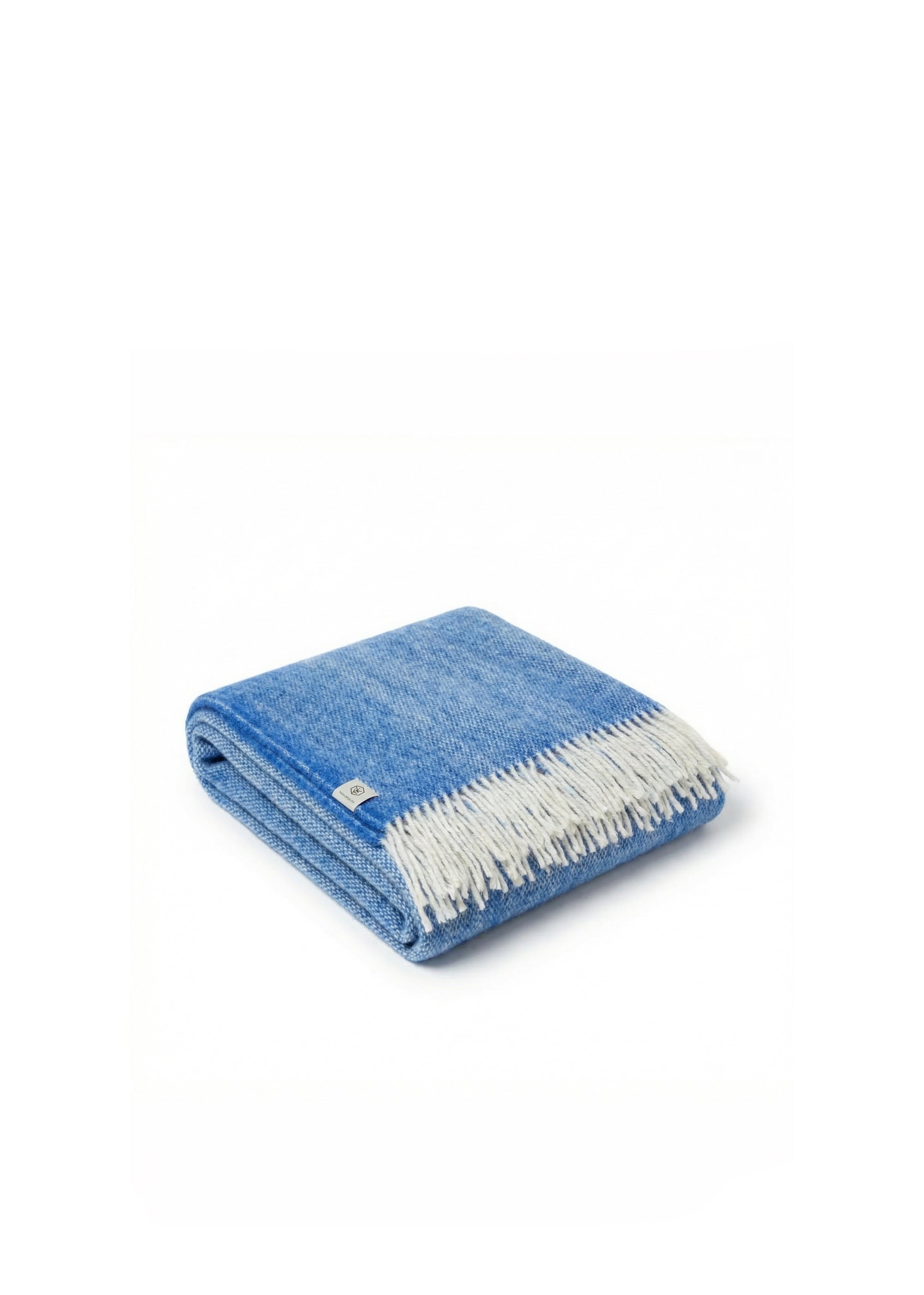 Blue and white wool throw blanket with fringed edges draped over a dark upholstered sofa