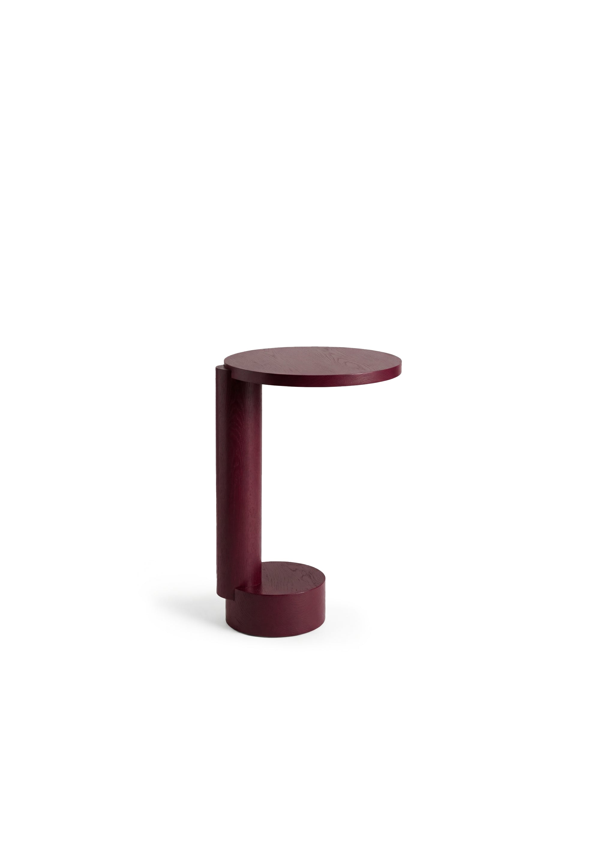 Side table with a ribbed glass vase and a single tall flower beside a grey armchair