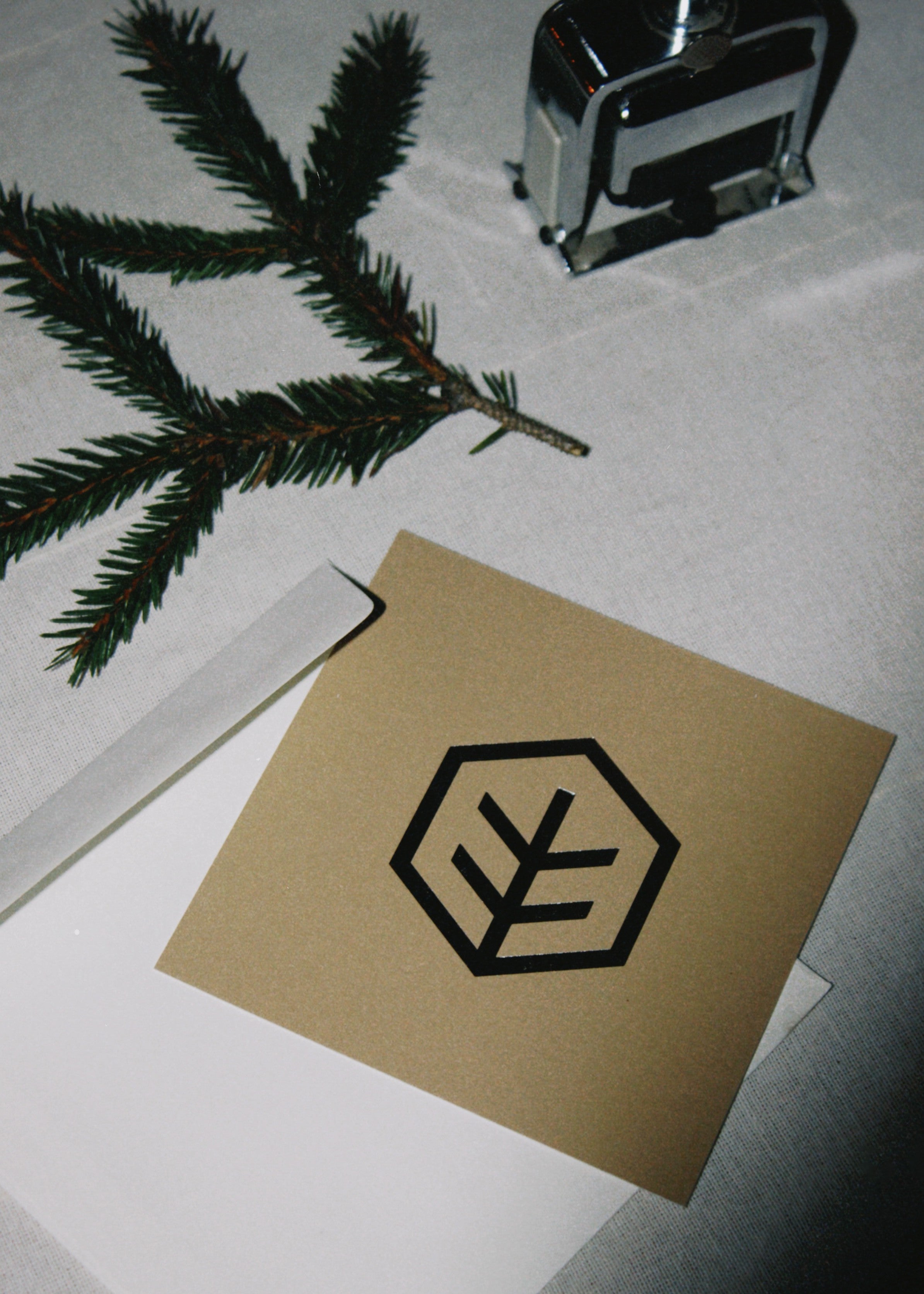 A set of printed cards arranged on a table, featuring a metallic embossed logo and minimal text layout.